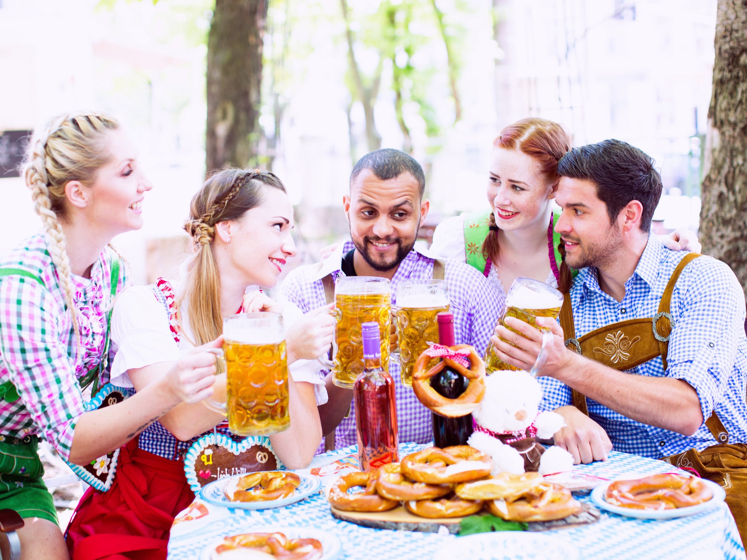 Bild: Freunde sitzen im Biergarten und stoßen mit einer Maß Bier an